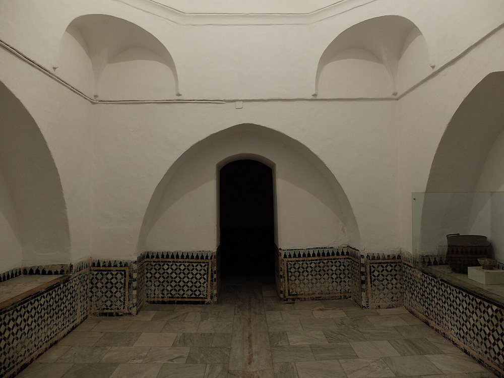 A domed hammam steam room with white walls, arched alcoves and patterned tiles